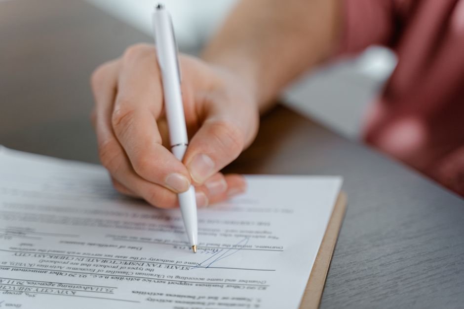 A via administrativa traz rapidez e economia para o casal. Close de mãos assinando documento de divórcio consensual em cartório de forma rápida.