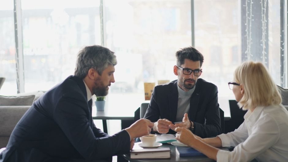 Pais discutindo acordos financeiros em um ambiente profissional. Mãe e pai conversando seriamente sobre responsabilidades financeiras em uma mesa de escritório