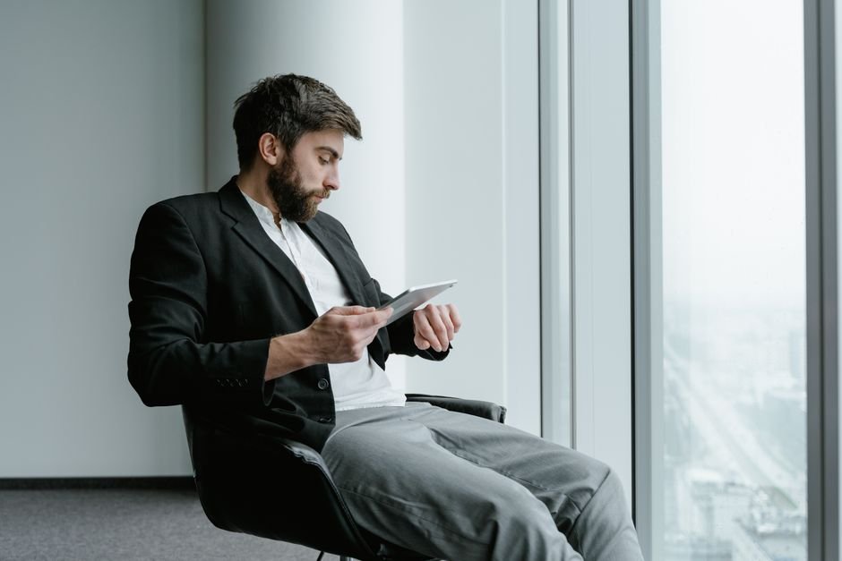 Advogado consultando processos para avaliar pedido de revisão. Profissional de direito consultando processos em um tablet dentro de um escritório iluminado