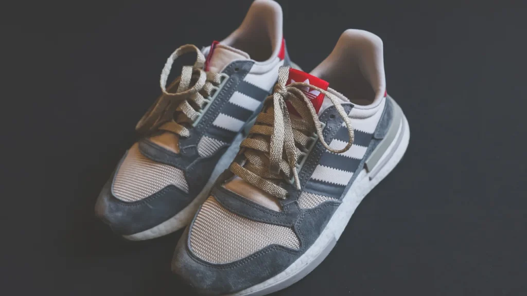 Par de tênis Adidas cinza com as três listras visíveis
