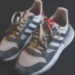 Par de tênis Adidas cinza com as três listras visíveis