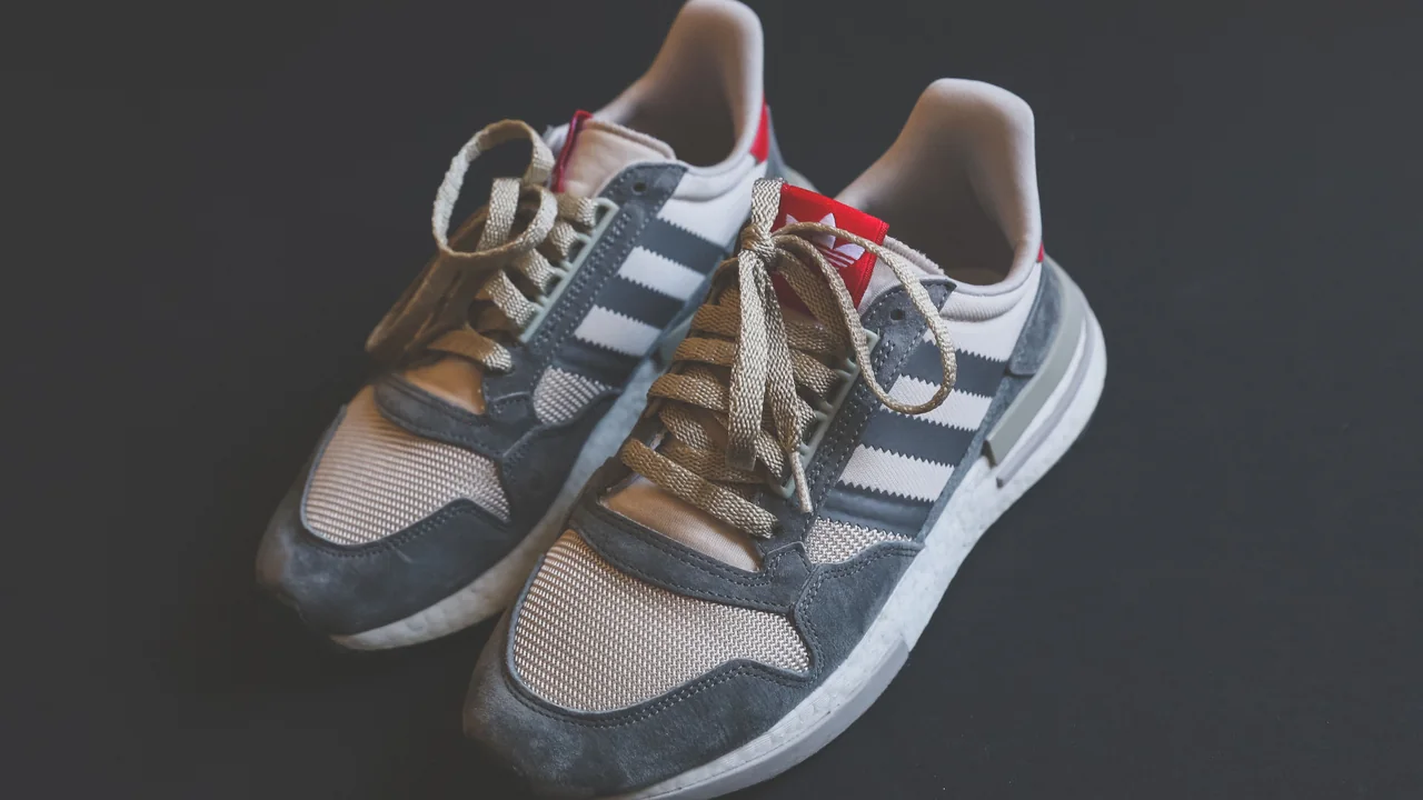 Par de tênis Adidas cinza com as três listras visíveis