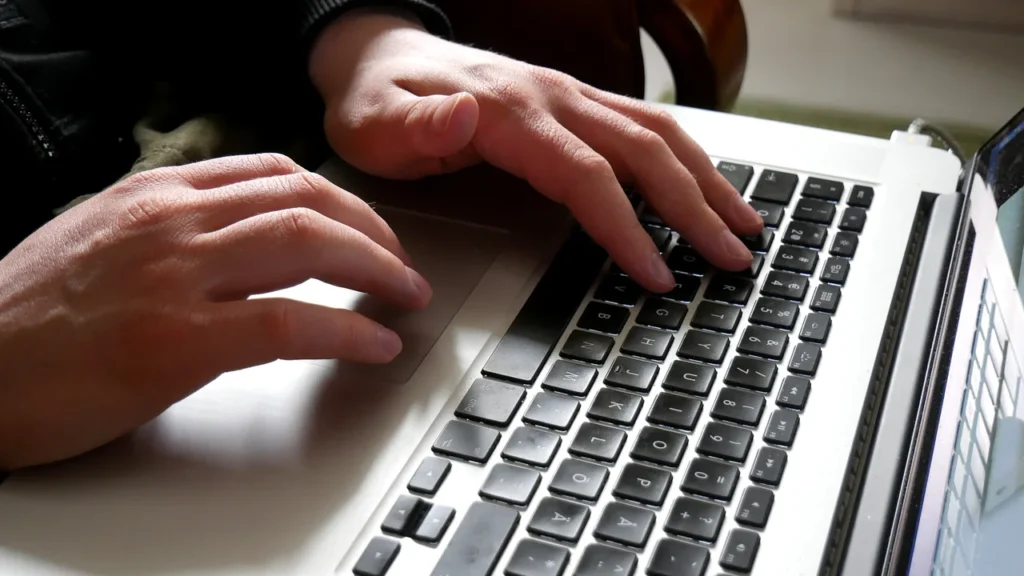 Mãos utilizando o teclado de um notebook sobre a mesa