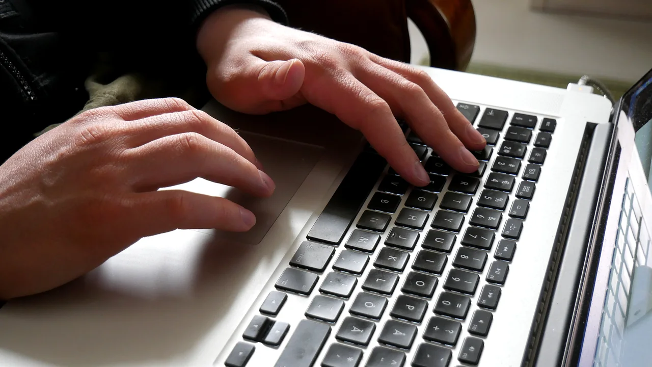 Mãos utilizando o teclado de um notebook sobre a mesa